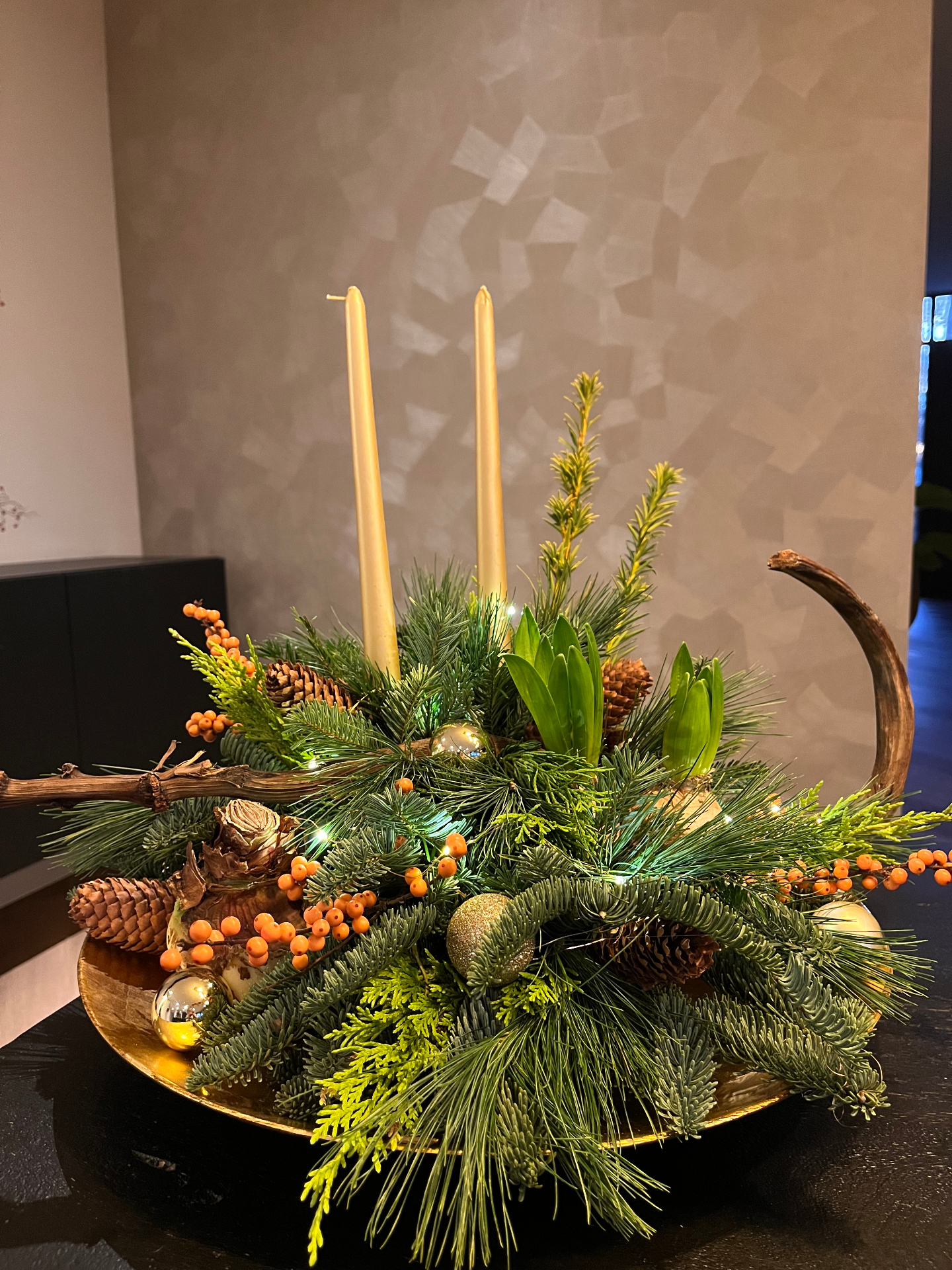 Kerststuk met dennengroen, oranje bessen, kaarsen en gouden accenten