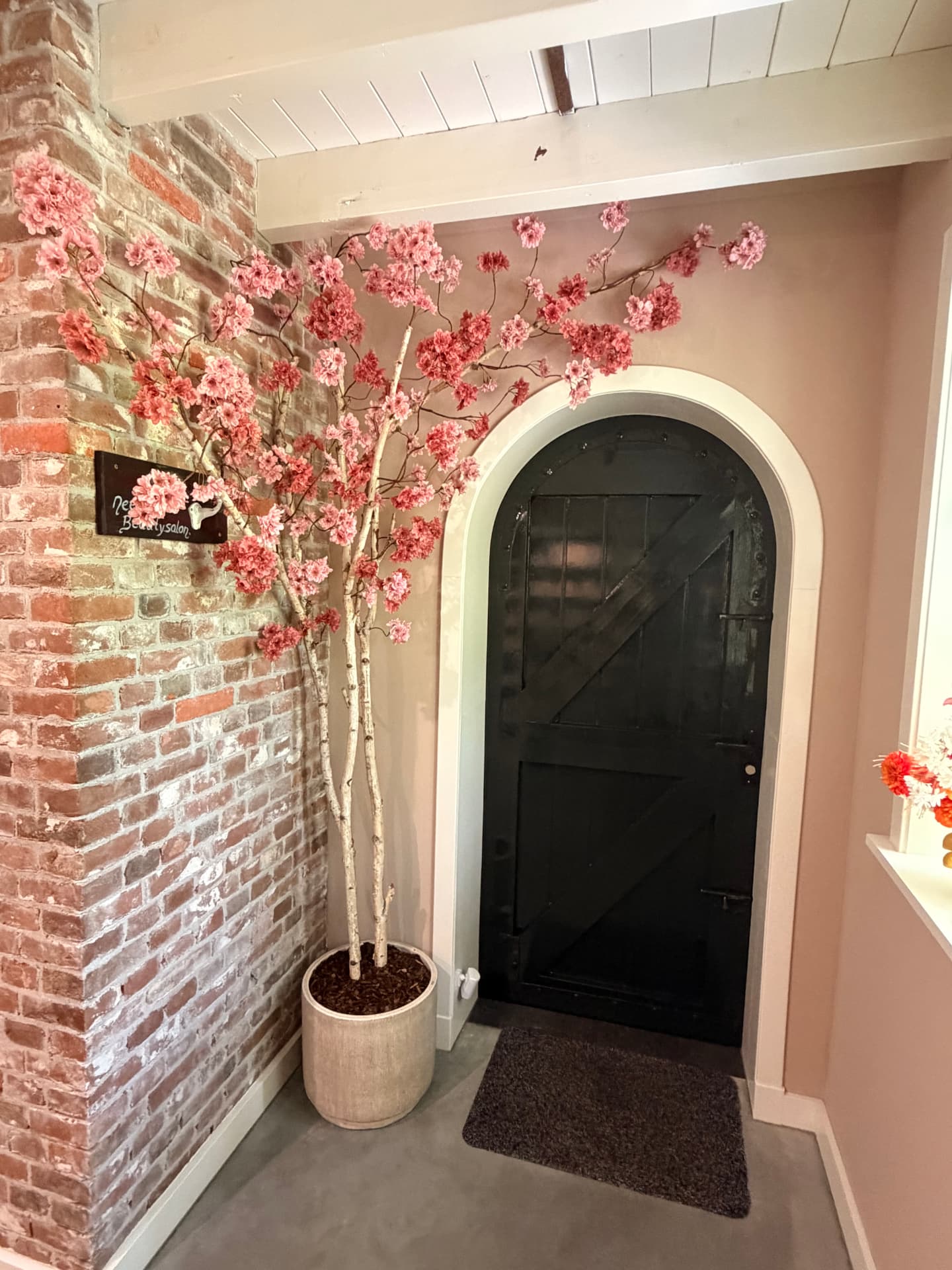 Bloesemboom op maat gemaakt voor een schoonheidssalon, met zachtroze bloesem op echte houten takken in een stijlvolle pot