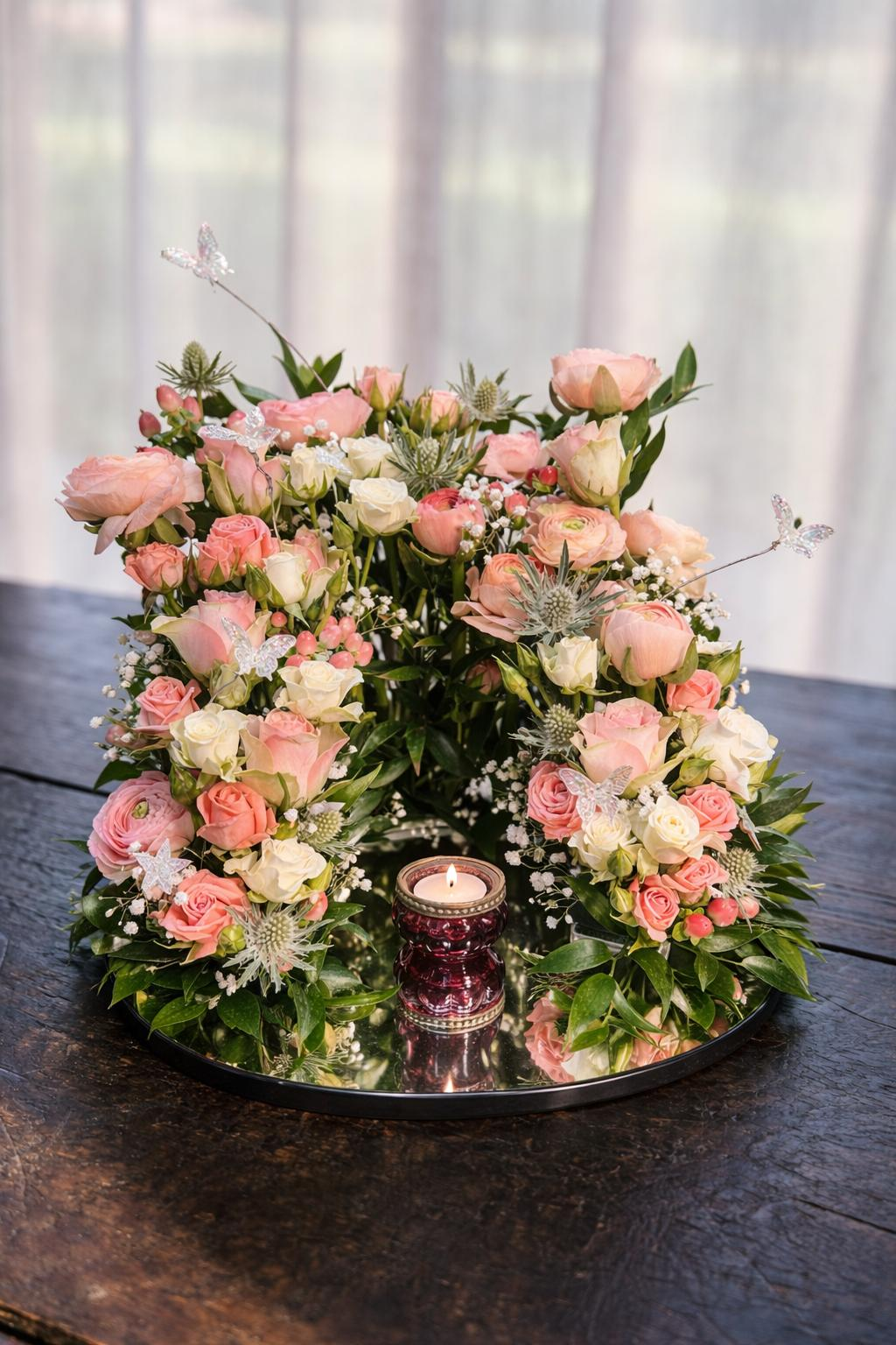 Urn-arrangement met roze en witte bloemen rond een kaarsje